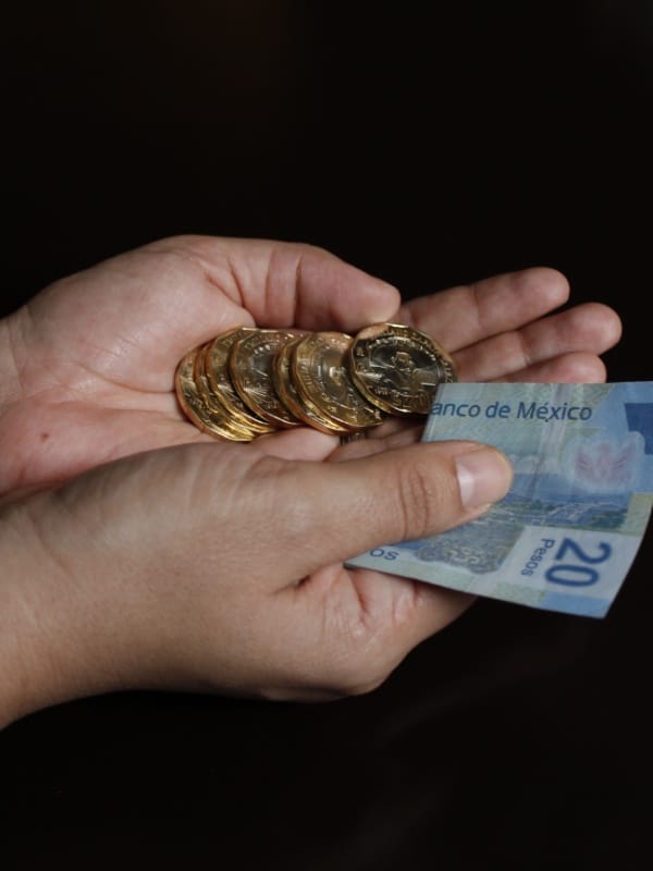 MANOS CON MONEDAS Y BILLETES REPRESENTANDO MÉTODOS DE PAGO Y CAMBIO DE DIVISAS EN MÉXICO